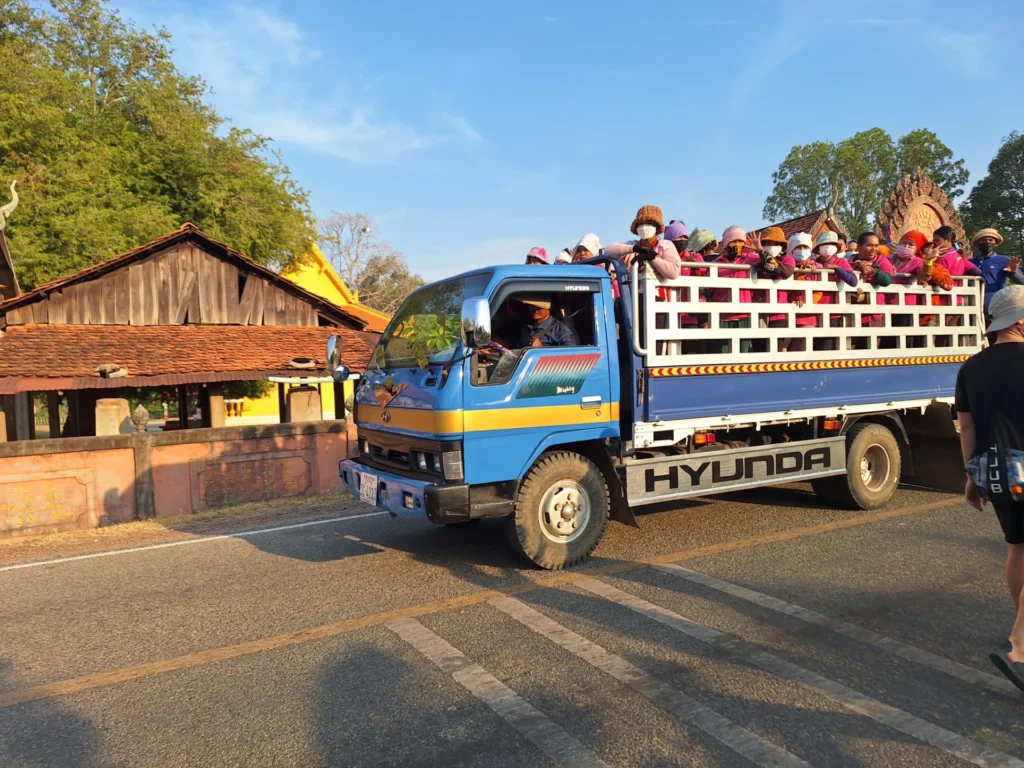An open-top truck transports factory workers home after the day's shift