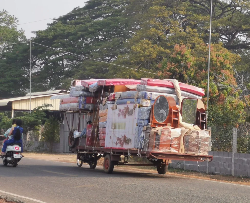 A tricycle carrying furniture about to topple over
